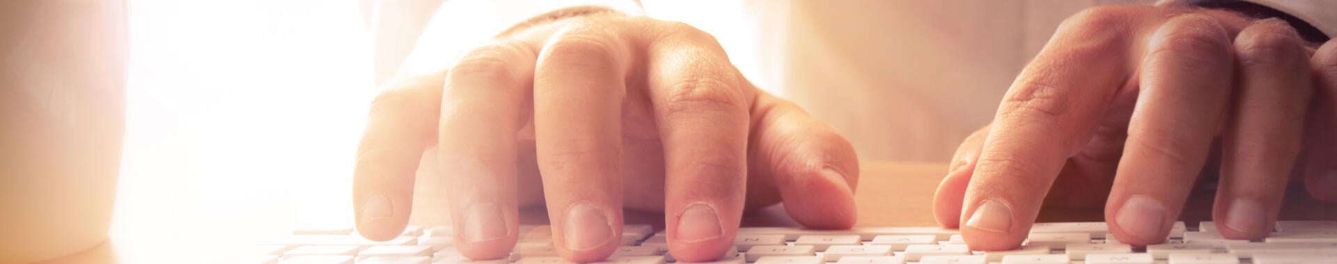 Closeup of hands typing on a computer keyboard