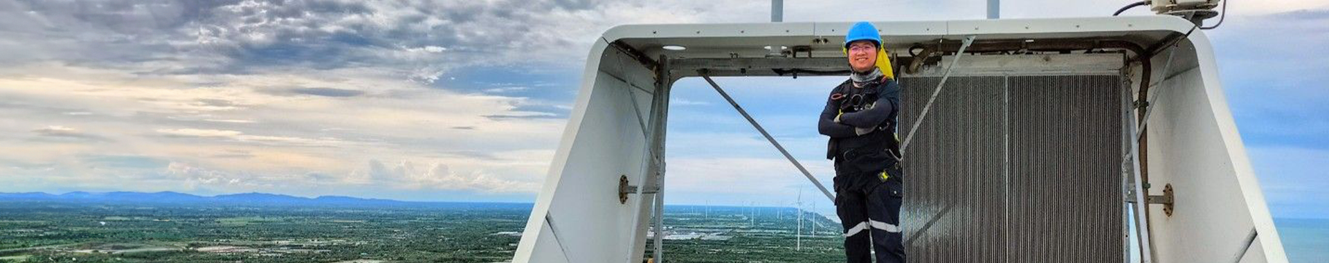 Engineer smiling at the top of a wind turbine