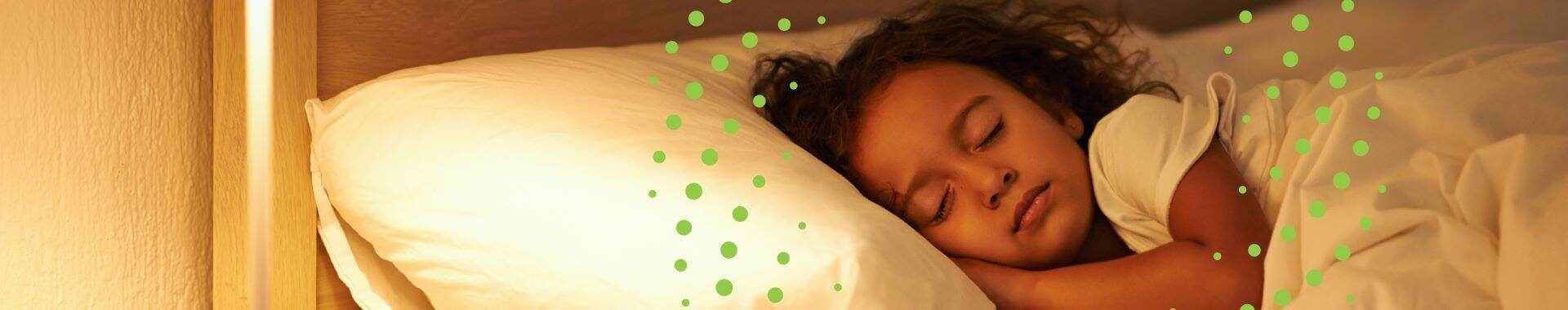 Child peacefully sleeping in bed with warm lighting from a bedside lamp