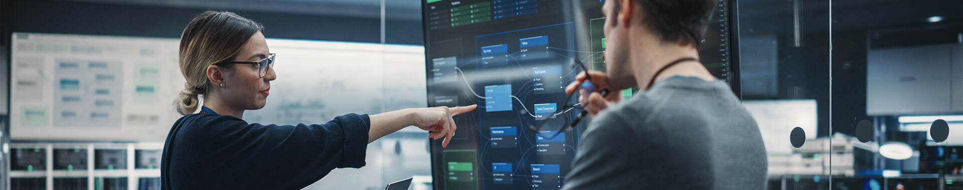 Two people reviewing data on a large screen