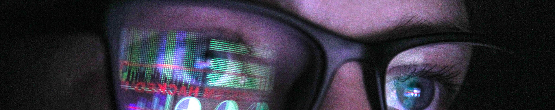 A person with glasses looking at data on a screen