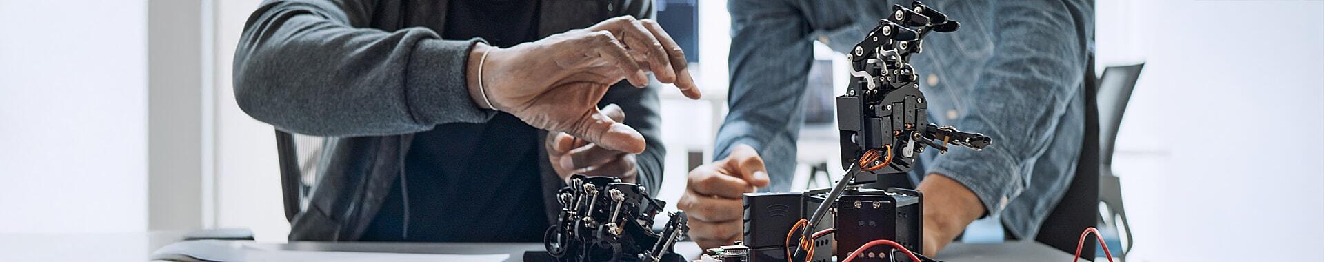 Two people assembling robotic hands in a lab.