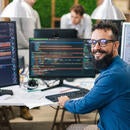 A happy person surrounded by multiple monitors