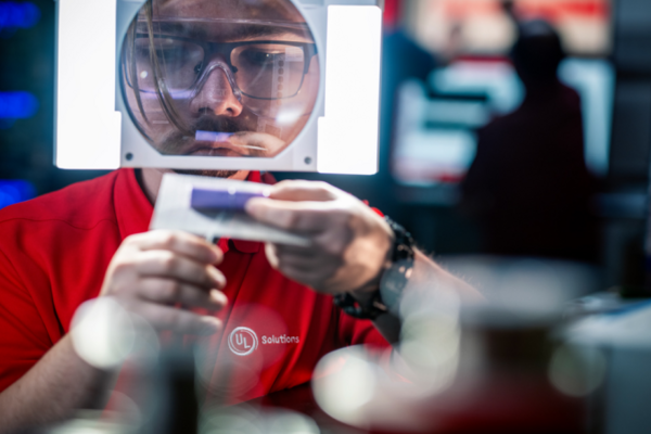 Man in red UL Solutions polo inspecting device