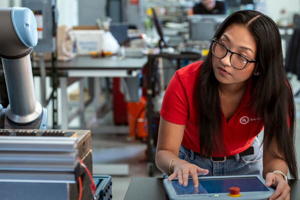 Engineer in red UL Solutions polo troubleshooting a robot arm