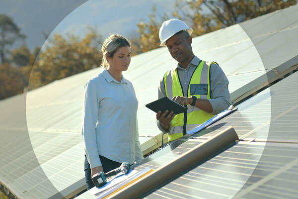 man and woman looking at tablet while on break from installing solar panels