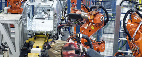 Vehicle factory manufacturing with robotic arms and automation.