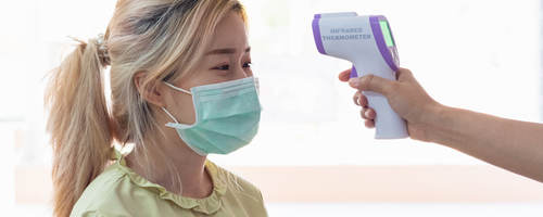 Lady wearing a mask getting temp scanned