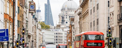 People walking on a busy street in London, England near St. Paul's Cathedral.