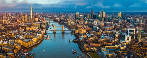 Golden hour aerial view of London’s skyline, including the Tower Bridge and famous skyscrapers.