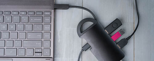 USB Type C adapter or hub connected to the laptop with various accessories – USB drives, HDMI, Ethernet, cables