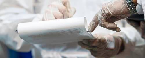 Two medical professionals' hands jotting down information on legal pad