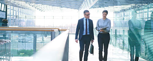 Two employees having a walking meeting in a glass building