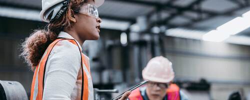 Female engineer wearing a helmet while standing in a factory 