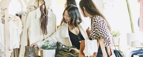 Friends admiring boots while shopping in clothing boutique