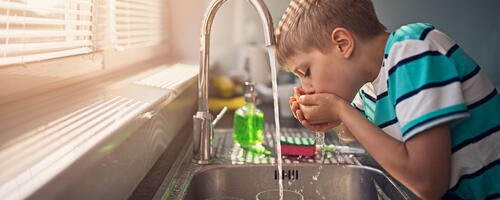 young person drinking tap water from the faucet