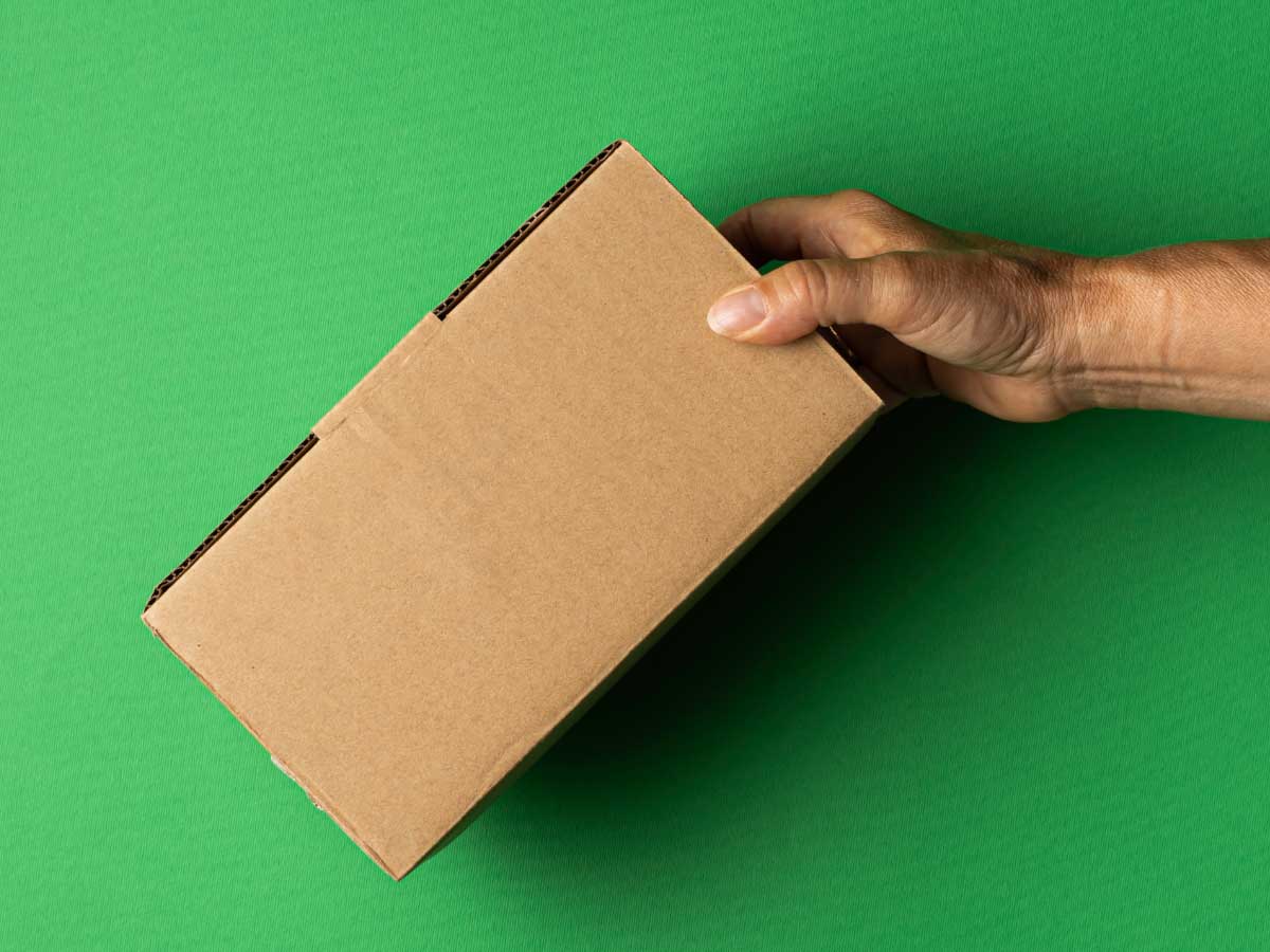 person's holding a rectangular box in front of a green background