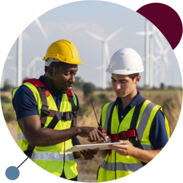 Two engineers having a discussion in front of a wind farm