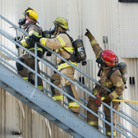 three firefighters going up exterior staircase