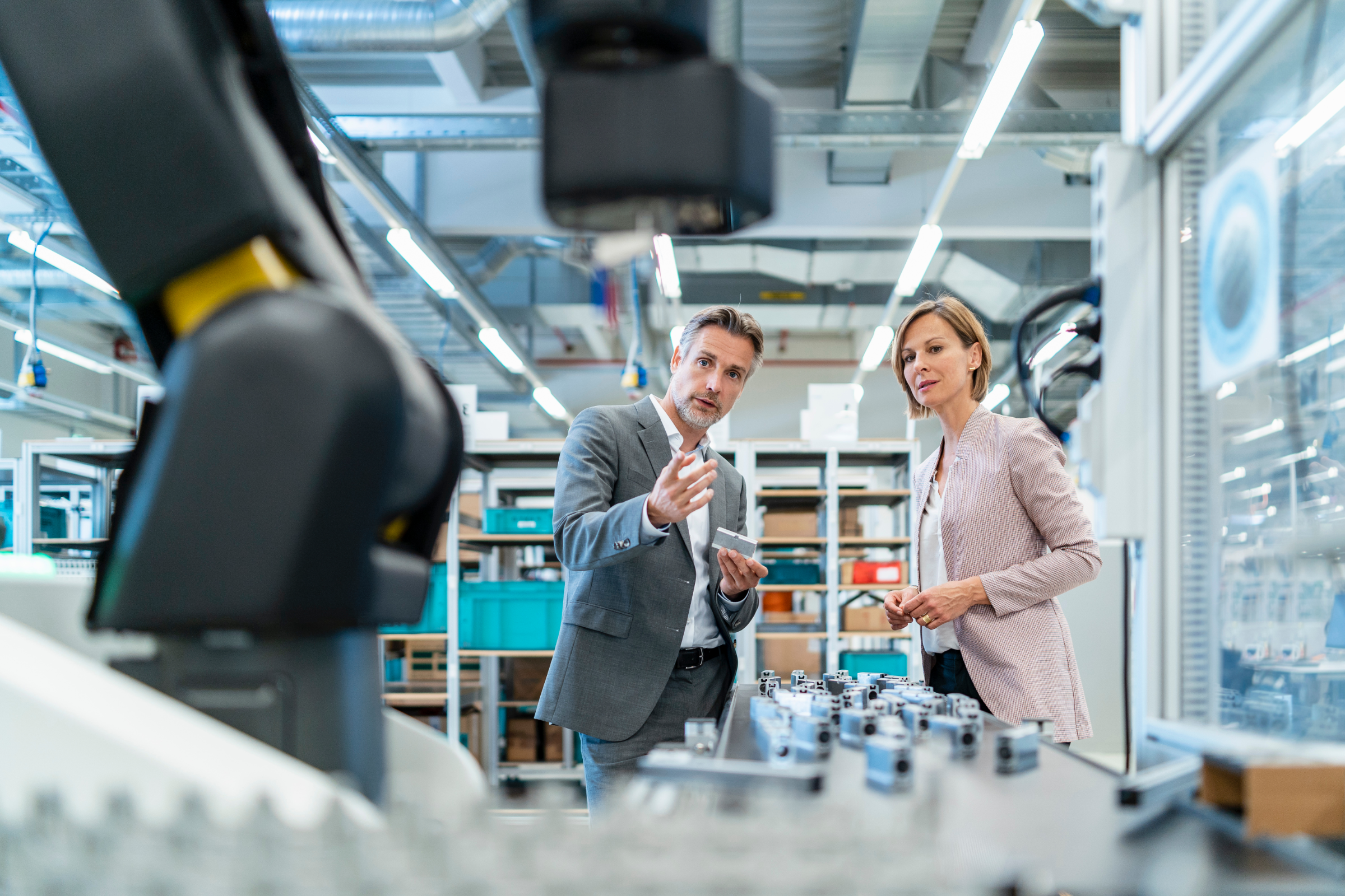 Workers next to a robotic arm