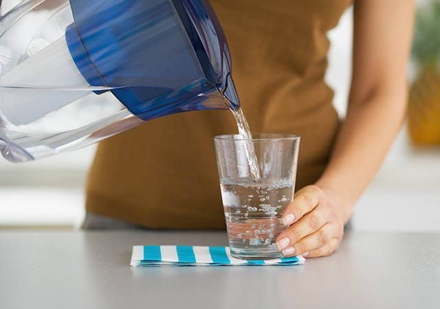 woman pouring a glass of water from a filter jug