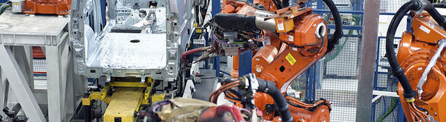 Vehicle factory manufacturing with robotic arms and automation.