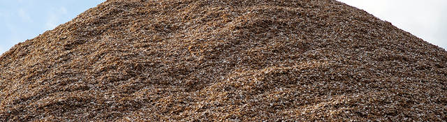 Pile of mulch woodchips against a blue sky