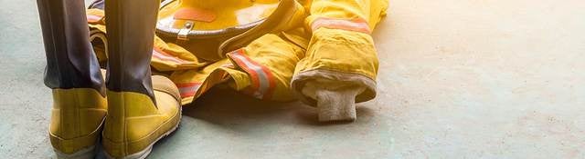 A yellow fireman’s uniform and boots laying on the ground. 