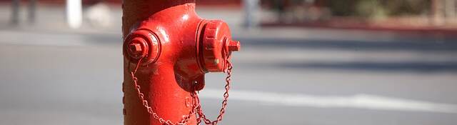 A bright red fire hydrant along a road.