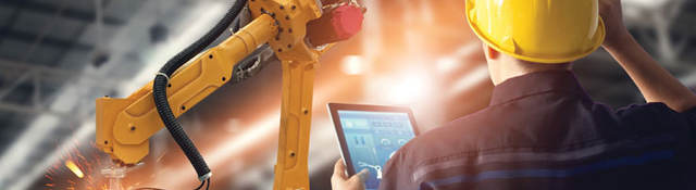 engineer in factory with tablet looking at robot arm