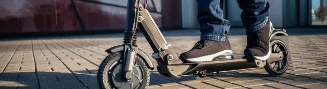 close up view of the legs of a man on an electric scooter.