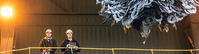 2 men overlooking a claw picking up recycleables
