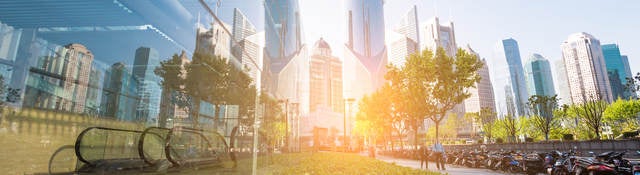 Panoramic and perspective view of high-rise buildings, where greenery and trees are reflected in the glass windows