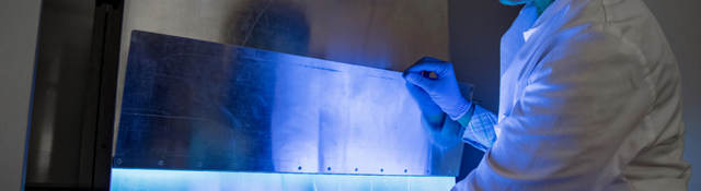 A woman uses UV light to inactivate harmful material on products.