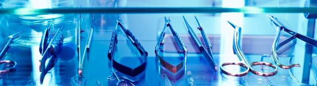 An array of medical devices sit within a cabinet basking in UV light.