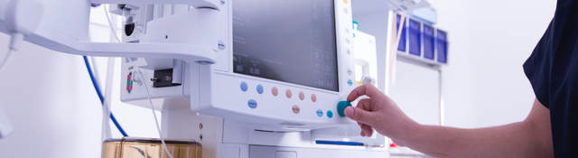 Technician monitoring equipment in hospital operating room