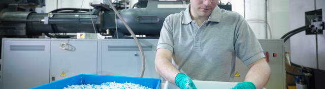 Worker inspecting recycled plastic in plastics factory