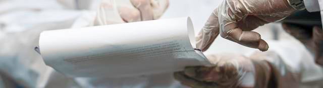 Two medical professionals' hands jotting down information on legal pad