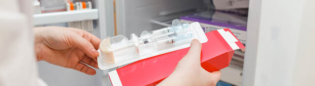 The doctor takes out medicine from the refrigerator with a disposable syringe