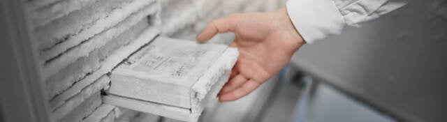 A scientist removing a sample from a laboratory freezer