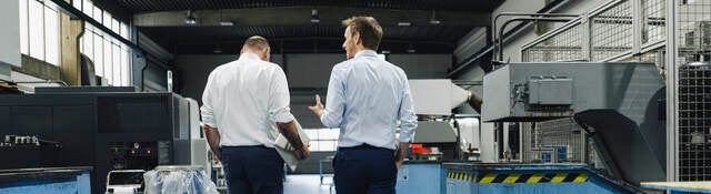 Two men walking and talking in a factory