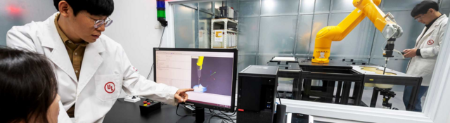 UL laboratory technicians inside lab with computer and robotic arm