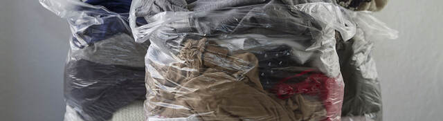 Clothes in plastic bags conveying promotion of recycling clothing, give it second life than become waste