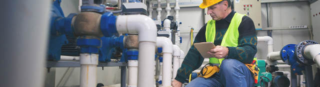 Senior repairman in boiler room checking pipes