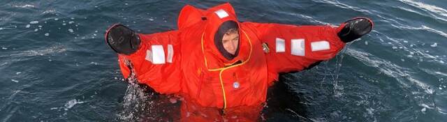 A person wearing an immersion suit and floating in water