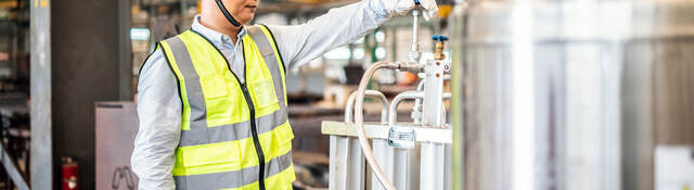 Worker operating a gas tank in a factory.  