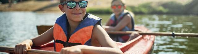 Children in life jackets rowing a canoe.