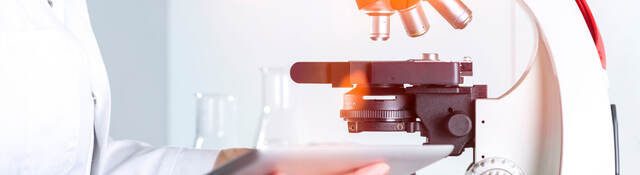 Scientist reviewing notes next to a microscope