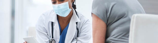 Doctor and patient looking at a tablet in an office. 