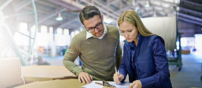 A Man and a woman look at something together in workplace
